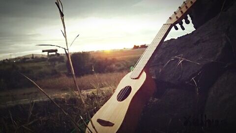 Close-up of guitar against sky during sunset