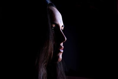 Close-up of thoughtful woman against black background