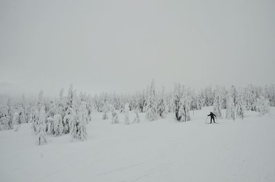 Person skiing on snow covered field against sky