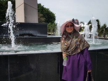 Portrait of woman standing against water fountain