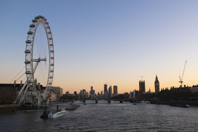 London eye skyline and a boat sailing down the famous river thames at sunset