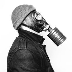 Side view of man wearing gas mask against white background