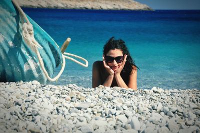 Portrait of young woman resting at beach on sunny day