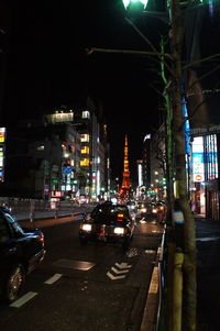 Cars on illuminated city street at night