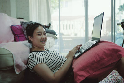 Portrait of smiling woman using laptop at home