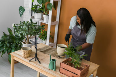 Side view of woman holding potted plant on table
