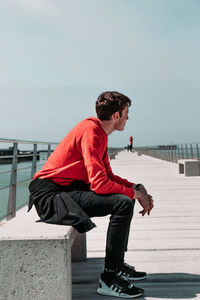 Man with umbrella against sea against clear sky