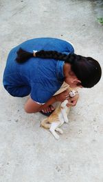 High angle view of woman embracing cat on footpath