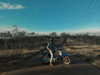 Bicycles riding motorcycle on road against sky