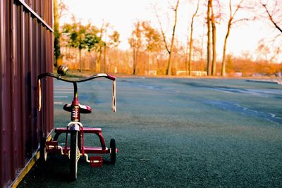 Tricycle parked on road against bare trees