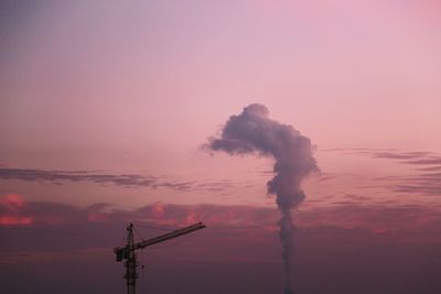 Silhouette of factory against sky at sunset