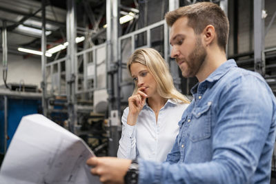 Business professionals brainstorming over plan in factory