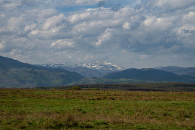 Scenic view of field and mountains against sky