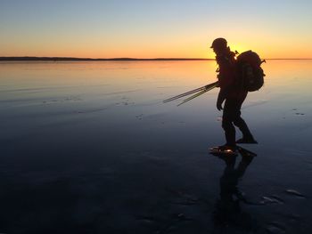Silhouette woman on beach against sky during sunset