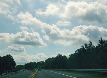 Road by trees against sky