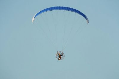 Low angle view of person flying powered hang glider in clear sky