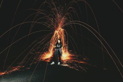 Teenage girl standing against firework display at night