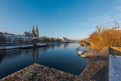 Bridge over river by buildings against sky