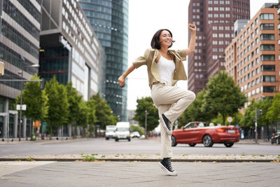 Side view of young woman walking on street in city