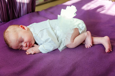 Portrait of cute baby lying on bed at home