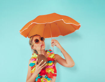 Portrait of smiling woman holding umbrella against clear sky