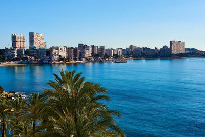 City at waterfront against blue sky