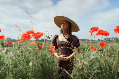 Young woman wearing hat standing amidst plants