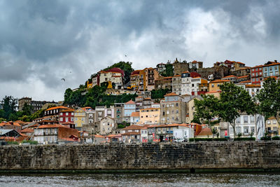 Houses by river against sky in town