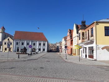 Street amidst buildings in city against clear blue sky