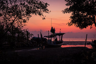 Silhouette boats moored in sea against sky during sunset