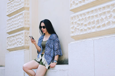 Young woman standing against wall