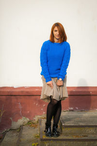 A beautiful young woman with red hair in a blue sweater made of natural wool 