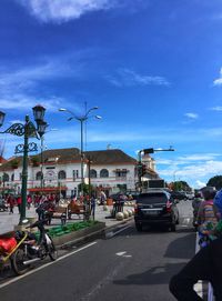 People on road in city against blue sky