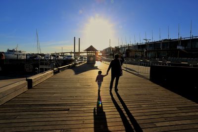 Rear view of people walking on pier