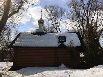 Built structure by bare trees and building against sky during winter