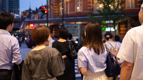 Rear view of people standing on street in city