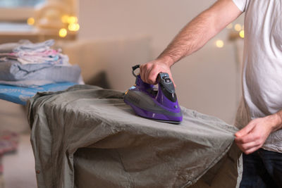 Midsection of man ironing shirt on board