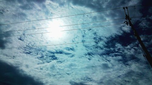 Low angle view of power lines against cloudy sky