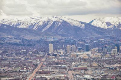 Aerial view of city and snowcapped mountains against sky