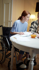 Young woman sitting on wheelchair at home