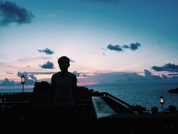 Silhouette people looking at sea against sky during sunset