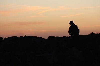 Silhouette man standing on cliff against sky during sunset