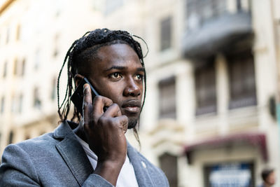 Close-up of young man talking on mobile phone in city