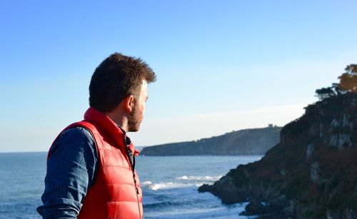 Young man against sea against clear blue sky