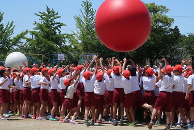 Students playing with red large ball in city