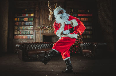 Full length of man wearing santa claus costume standing at home