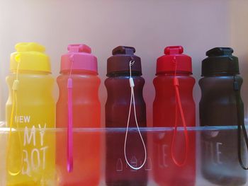 Close-up of multi colored bottles on shelf against wall