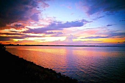 Scenic view of sea against cloudy sky at sunset