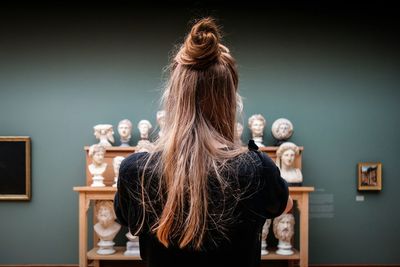 Woman with long hair standing in front of sculptures