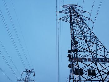 Low angle view of electricity pylon against clear blue sky